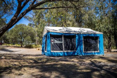 İzole edilmiş bir kamp alanında kamp yapan mavi çadırlı çadırlar ve karavanlar.