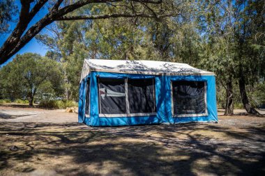 İzole edilmiş bir kamp alanında kamp yapan mavi çadırlı çadırlar ve karavanlar.