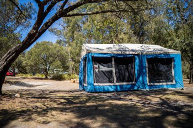 İzole edilmiş bir kamp alanında kamp yapan mavi çadırlı çadırlar ve karavanlar.