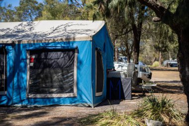 İzole edilmiş bir kamp alanında kamp yapan mavi çadırlı çadırlar ve karavanlar.