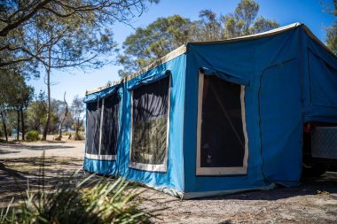 İzole edilmiş bir kamp alanında kamp yapan mavi çadırlı çadırlar ve karavanlar.