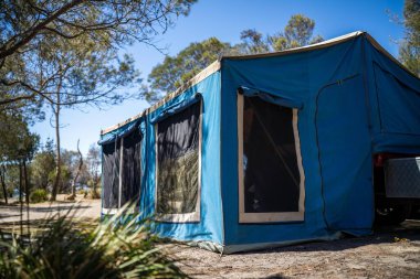İzole edilmiş bir kamp alanında kamp yapan mavi çadırlı çadırlar ve karavanlar.