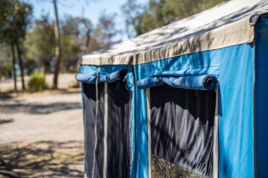 İzole edilmiş bir kamp alanında kamp yapan mavi çadırlı çadırlar ve karavanlar.