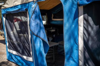 İzole edilmiş bir kamp alanında kamp yapan mavi çadırlı çadırlar ve karavanlar.