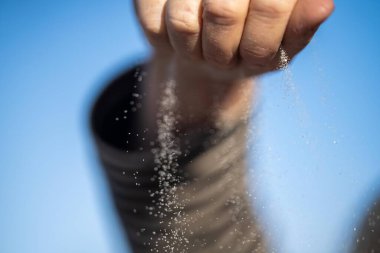 Avusturalya 'daki kum taneciklerinin arasından bir ele kum dökülüyor.