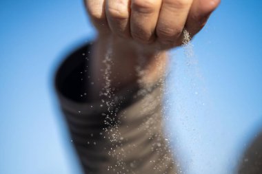 Avusturalya 'daki kum taneciklerinin arasından bir ele kum dökülüyor.