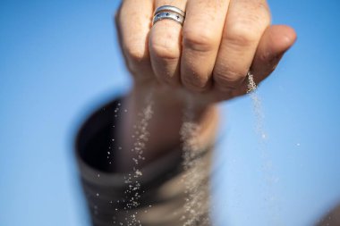 Avusturalya 'daki kum taneciklerinin arasından bir ele kum dökülüyor.