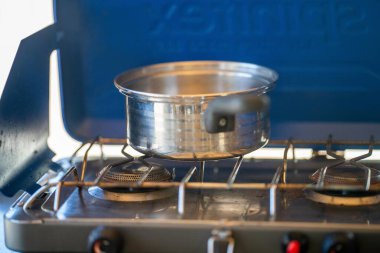 Ormandaki bir kamp alanında, gaz ocağında yemek pişirmek. Mavi bir karavanda yemek pişirmek. Milli parktaki çalılıklarda bir çadırda eğleniyorum. 