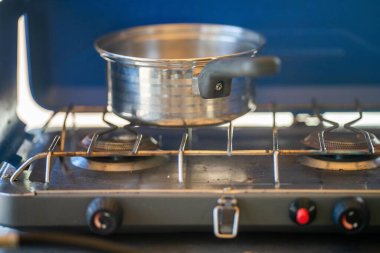 Ormandaki bir kamp alanında, gaz ocağında yemek pişirmek. Mavi bir karavanda yemek pişirmek. Milli parktaki çalılıklarda bir çadırda eğleniyorum. 