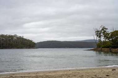  Kumsalda, denizin kıyısında dalgalar ve dağlar var. 