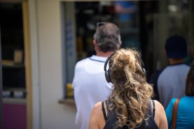 Kadınlar yemek için sıraya girerken bir kafede kulaklık takıyorlar.