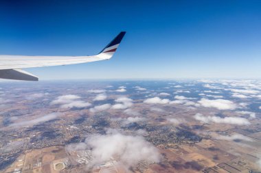 Avustralya 'nın üzerindeki bulutlara bakan bir uçak penceresi. 