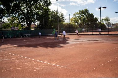 Arkadaşlar kil sahada tenis oynuyorlar, kil kortu sulayıp avlıyorlar. Avustralya 'da tenis kortu yapmak.