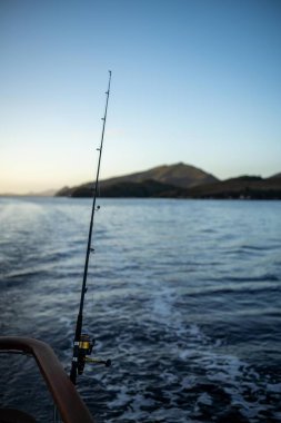 Günbatımında okyanus dalgalarında balık tutmak