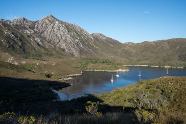 Tazmanya Avustralya 'daki Davey Ulusal Parkı' nda dağlar ve nehirler var. Yeni Zelanda 'da akşam bir körfezde tekneler
