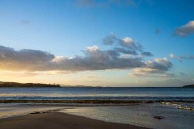 Gün doğumu sahile yansıyor. Dalgalar içeri girerken ve su kumda ilerlerken, Avustralya 'da sakinleştiren dalgalar.