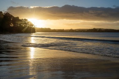 Gün doğumu sahile yansıyor. Dalgalar içeri girerken ve su kumda ilerlerken, Avustralya 'da sakinleştiren dalgalar.