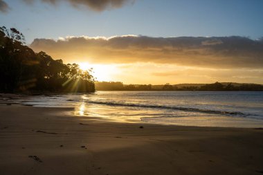 Gün doğumu sahile yansıyor. Dalgalar içeri girerken ve su kumda ilerlerken, Avustralya 'da sakinleştiren dalgalar.
