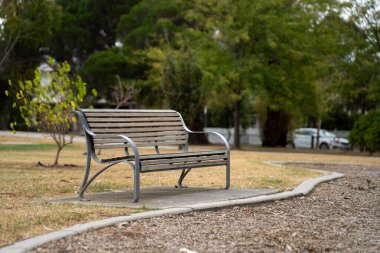 Güneşli bir bahar gününde futbol spor ovalı etrafında park bankları ve koltuklar. Formda kalmak için spor yapan insanlar.