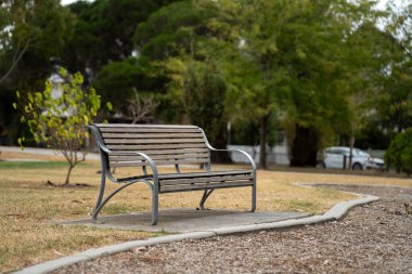 Güneşli bir bahar gününde futbol spor ovalı etrafında park bankları ve koltuklar. Formda kalmak için spor yapan insanlar.