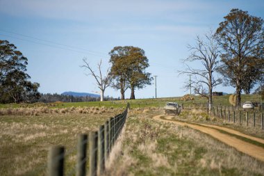 driving down a dirt road gravel road in outback australia in a ute truck on a farm a wire fence clipart