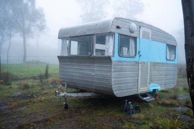 Antika bir karavan Avustralya 'daki ormanda sisli bir tatil için kamp alanının dışında kamp yapıyor.