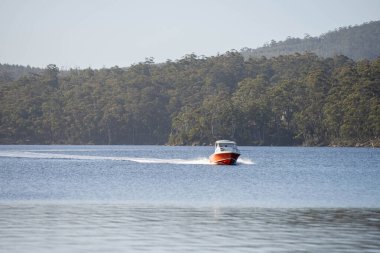 Denizdeki teneke sandal Avustralya 'daki bir milli parktaki nehirde dalgalanan bir teknenin arkasında uyanacak. Yazın kumsal, çölde hızla batan karanlık.