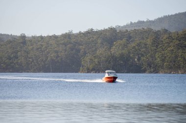 Denizdeki teneke sandal Avustralya 'daki bir milli parktaki nehirde dalgalanan bir teknenin arkasında uyanacak. Yazın kumsal, çölde hızla batan karanlık.
