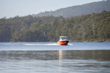 Denizdeki teneke sandal Avustralya 'daki bir milli parktaki nehirde dalgalanan bir teknenin arkasında uyanacak. Yazın kumsal, çölde hızla batan karanlık.