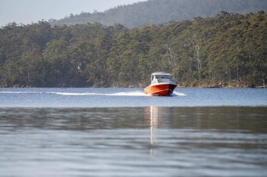 Denizdeki teneke sandal Avustralya 'daki bir milli parktaki nehirde dalgalanan bir teknenin arkasında uyanacak. Yazın kumsal, çölde hızla batan karanlık.