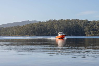 Denizdeki teneke sandal Avustralya 'daki bir milli parktaki nehirde dalgalanan bir teknenin arkasında uyanacak. Yazın kumsal, çölde hızla batan karanlık.