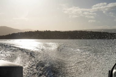 Denizdeki teneke sandal Avustralya 'daki bir milli parktaki nehirde dalgalanan bir teknenin arkasında uyanacak. Yazın kumsal, çölde hızla batan karanlık.