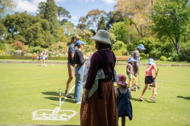 family playing croquet in a lawn playing field in australia in summer clipart