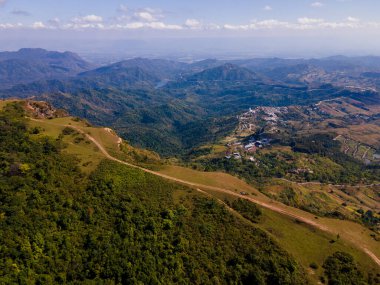 Dağ zirvesinin havadan görünüşü ve yeşil ormanın yakınındaki uçurumlar.