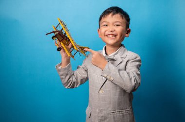 the studio shot isolated image of the boy playing the miniture airplane with the blue backdrop