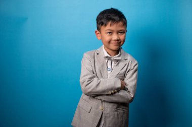 the studio shot isolated image of the boy wearing suit with the blue backdrop