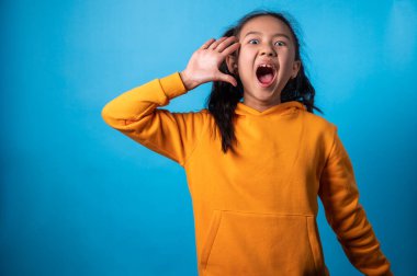 the studio isolated a portrait image of the acting of a happy girl with a blue backdrop.
