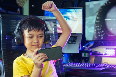 Çocuk akıllı telefon ve bilgisayar aracılığıyla evde bir video oyunu oynuyor. Teknoloji, internet, oyun ve eğlence kavramı