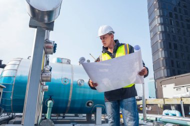 Görüntü, petrokimyasal bir tesisteki boru hatlarını inceleyen yetenekli bir mühendisi yakalıyor. Petrokimyasallar, mühendislik ve endüstriyel denetim ile ilgili proje kavramı.