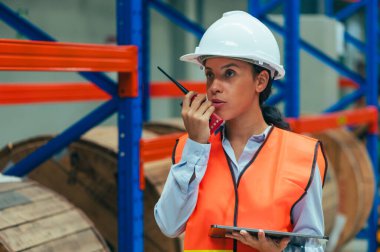 İşçi, yoğun bir deponun organize kaosunun ortasında tasvir edilir. Envanter yönetimi, sipariş yerine getirilmesi veya lojistik operasyonlar gibi görevlerle meşguldür..