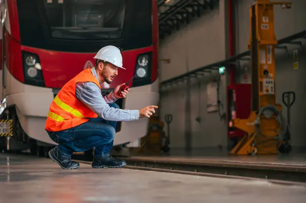 The engineer is captured in the dynamic environment of a train and railway garage, immersed in the meticulous tasks of maintenance, repair, or inspection.