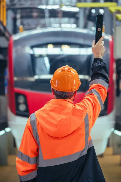 エンジニアは メンテナンス または検査の細心の仕事に没頭した列車や鉄道ガレージの動的環境で捕獲されます ロイヤリティフリーのストック画像