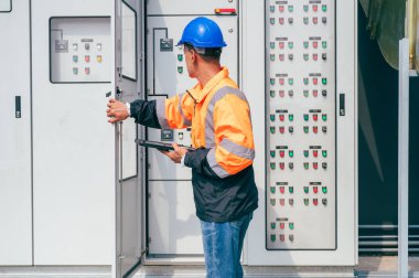 Elektrikçi, elektrik sisteminin güvenliği ve istikrarına odaklanan büyük ölçekli bir endüstriyel elektrik kontrol sistemini inceliyor..