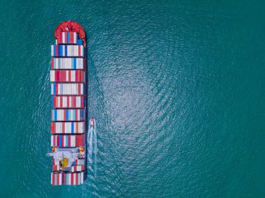 Yüklenen ve boşaltılan bir kargo gemisinin havadan bakış açısı hareketli bir limanda ve anakaradan denize açılışı