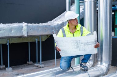 Teknisyen, bir inşaat projesi sırasında boru hattının bir bölümünü dikkatle inceleyerek, altyapı gelişimindeki güvenlik ve hassasiyeti vurguladı.