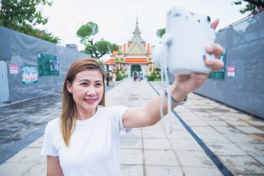 Güney Asyalı bir grup turist ellerinde harita tutarken ve yön ararken, ikonik Wat Phra Kaew tapınağı Bangkok, Tayland 'da tatil maceralarının tadını çıkarıyorlar..