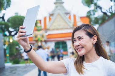 Güney Asyalı bir grup turist ellerinde harita tutarken ve yön ararken, ikonik Wat Phra Kaew tapınağı Bangkok, Tayland 'da tatil maceralarının tadını çıkarıyorlar..