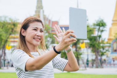 Güney Asyalı bir grup turist ellerinde harita tutarken ve yön ararken, ikonik Wat Phra Kaew tapınağı Bangkok, Tayland 'da tatil maceralarının tadını çıkarıyorlar..