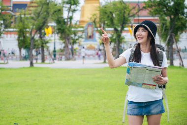 Güney Asyalı bir grup turist ellerinde harita tutarken ve yön ararken, ikonik Wat Phra Kaew tapınağı Bangkok, Tayland 'da tatil maceralarının tadını çıkarıyorlar..