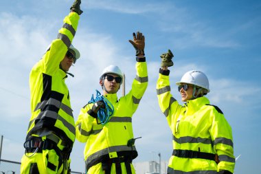 Güvenlik teçhizatı kullanan bir mühendis yenilenebilir enerji alanındaki rüzgar türbininin tabanını yakından inceler..